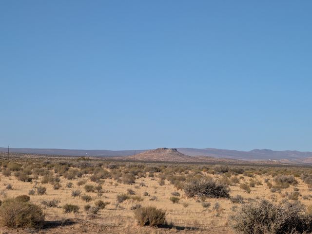 Wide desert flats stretching to distant hills under an empty blue sky.