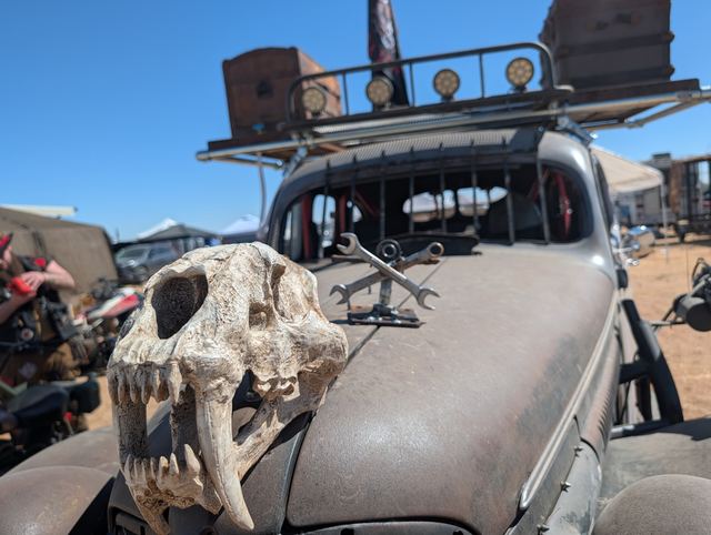 Close-up of a fanged animal skull mounted on the war car's hood next to a crossed-wrench emblem.