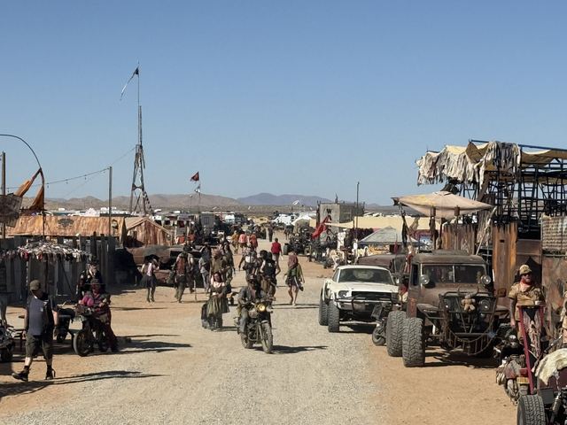 A busy main street lined with shacks, motorcycles and war rigs rolling through the crowd.