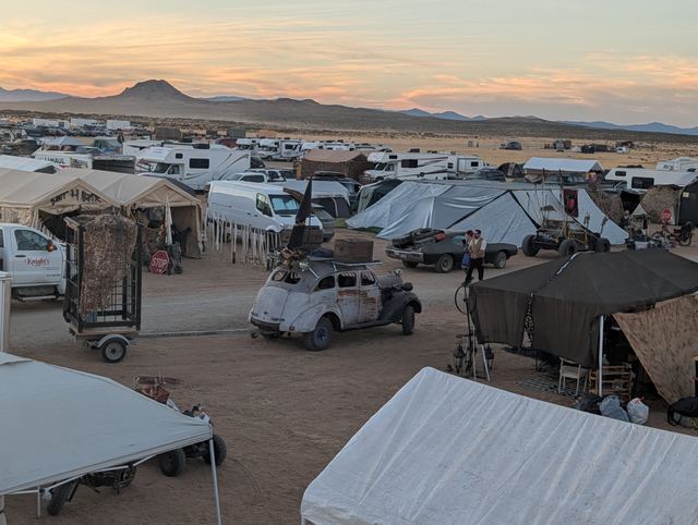 Camp lanes from above, a war rig with a flag parked between tents.