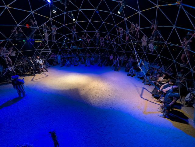 Fighters crossing the lit Thunderdome floor as the packed dome watches.