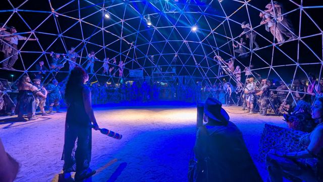 Wide Thunderdome panorama, spectators climbing the struts all around.