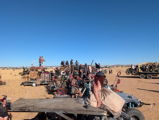 Rows of decorated war rigs gathered on the open desert flats, riders perched on top.