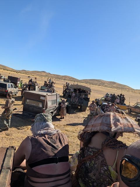 Riders on a vehicle roof looking out over the convoy.