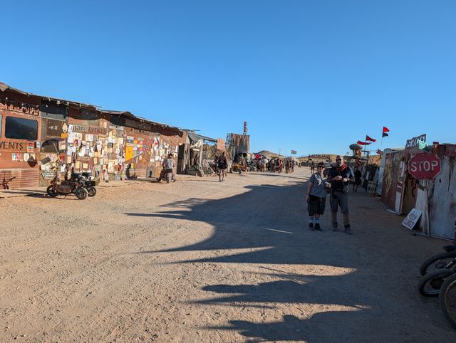 A town street lined with flyer-covered shacks and a stop sign.