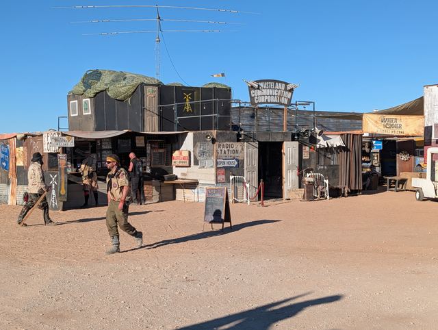 Wastelanders walking past the Wasteland Commerce Corporation building.