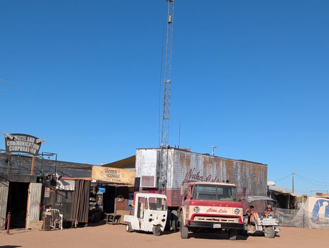 A tall radio tower over shacks, an old red fire truck parked out front.