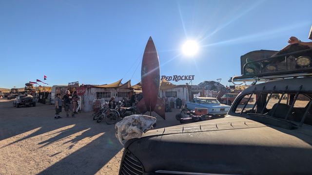 The war car parked near the Red Rocket, a towering rocket sculpture behind.