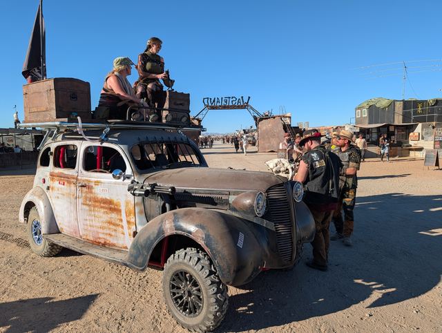 The war car with two riders on its roof rack, Grandpa standing beside it.