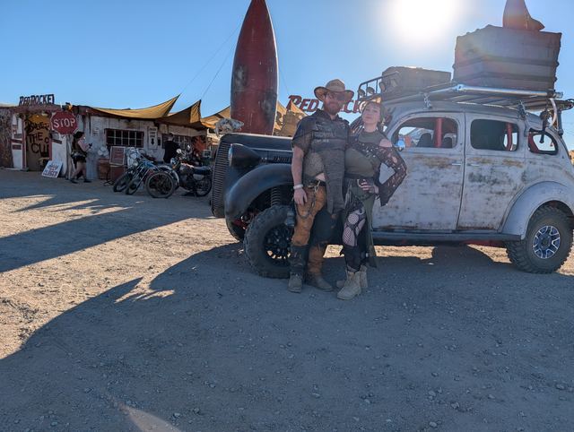 A couple poses in front of the war car at Red Rocket.