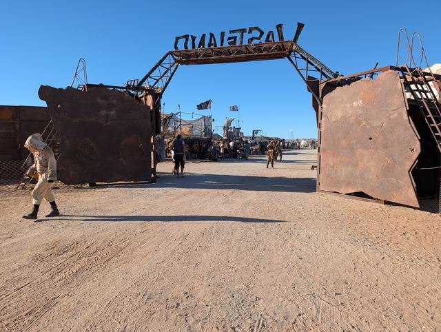 The Wasteland gate from inside town, wastelanders walking through.