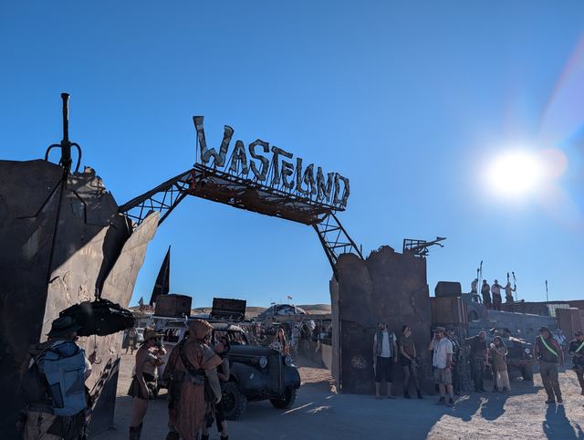The war car pulling up beneath the Wasteland gate as the crowd watches.