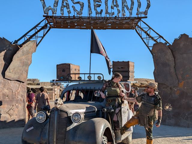 Crew members climb on and off the war car under the gate.