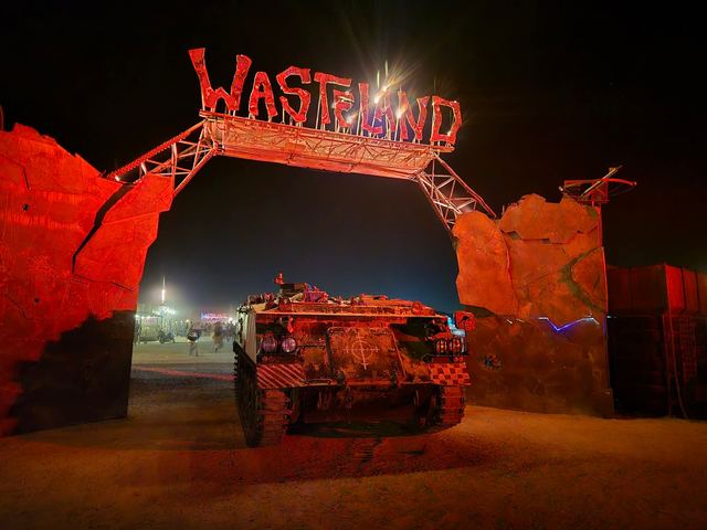 An armored tank-like vehicle under the red-lit Wasteland gate at night.