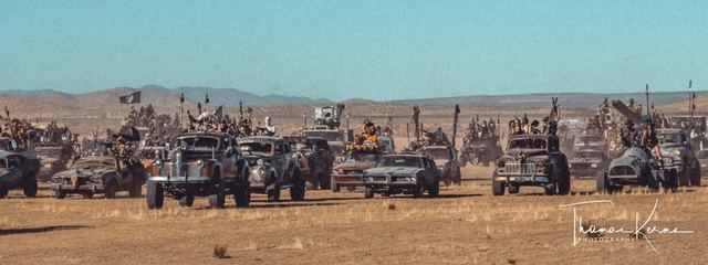 A line of war rigs across the open flats. Photographer's watermark in the corner.