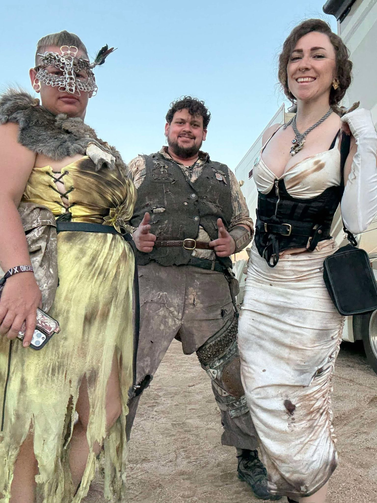 The same trio at dusk, smiling this time, thumbs up in the middle.